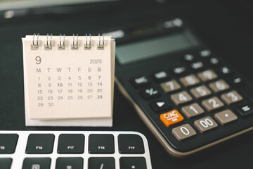 Calendar of September 2025 with Calculator and Keyboard on Office Desk. standing desk calendar showing the month of SEP 2025. planning, finance, budgeting, deadlines, and office organization.