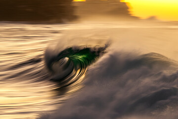 A motion blur photograph of a powerful ocean wave breaking at sunrise at Bronte Beach, Sydney....