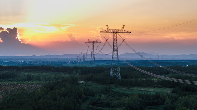 Sunset scene with high-voltage transmission towers in the field