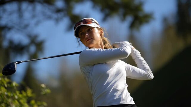 A woman golfer in action, swinging a golf club with precision, on a sunny day