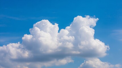 Naklejka premium Fluffy cumulus cloud against a clear blue sky, creating a serene summer atmosphere. 