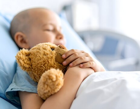 A sick child lying in bed in a hospital with his favorite stuffed toy. Bald child fights illness, enjoys a happy moment