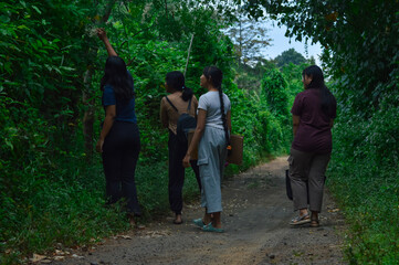 The group pauses to admire small blooming flowers along the roadside, soaking in the beauty of the...