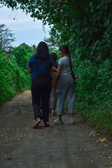As they walk along the leafy path, the girls lean in to observe clusters of roadside greenery and...