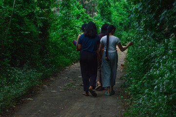 The girls stroll down the quiet forest path, pausing occasionally to observe wild plants growing...