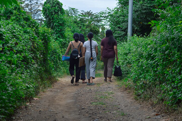 With yoga mats slung over their shoulders, the girls take a slow stroll through the forest path,...