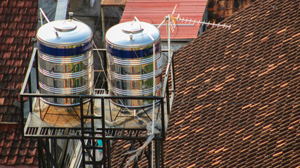 Two stainless steel water tanks mounted on metal platforms above the tiled roof. The tanks are...
