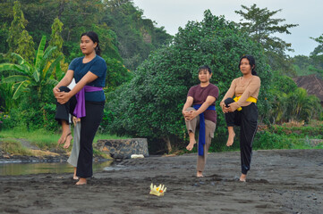 One-legged yoga pose held with both hands grasping shin under the knee as the girls stand tall near...