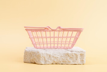 Empty shopping basket on stone podium against a beige wall background, ideal for mockups and...