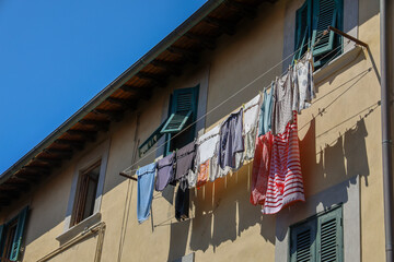 A clotheslines with pulley outside the windows with clothes airing out to dry on residential building in Italy.
