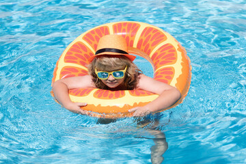 Child in swimming pool on inflatable ring. Kid swim with orange float. Water toy, healthy outdoor...