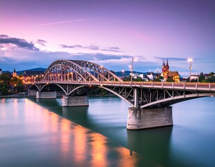Obraz premium Sunset view of a steel arch bridge spanning a calm river, with city skyline and church in the background
