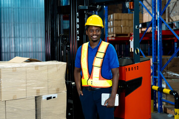 African male adult warehouse worker standing beside packed boxes smiling confidently wearing safety...
