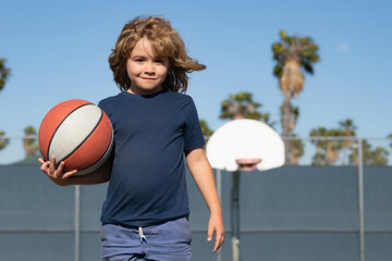 Child playing basketball on outdoor court. Happy child boy hold basketball ball. Summer sport kids....