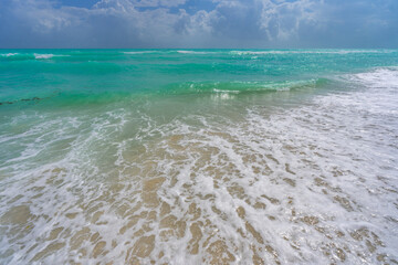 Turquoise sea water wave motion. Summer beach. Calm sea. Luxury seaside resort. Bright sky and waves on beach. Beautiful foamy shoreline. Sea background. Blue ocean. Sandy beach. Sea waves.