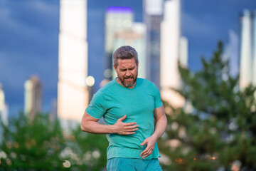 A man having a heart attack outdoors. A man clutching his chest in pain. A man from a heart attack...