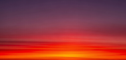 Abstract blurred sunset sky with orange, red, and purple gradient colors, creating a dreamy atmosphere with soft transitions and warm tones ideal for modern backgrounds or calm designs.
