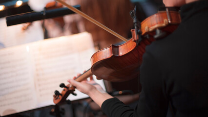 girl playing violin in orchestra on stage