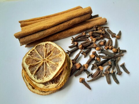 dried sliced lemon, cloves and cinnamon sticks on white - Powered by Adobe