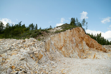 Natural marble quarry with fractured rock face and many loose stones.