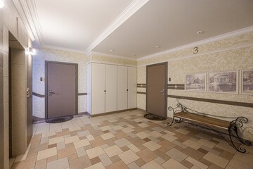 indoor lobby space featuring doors, tiled floors, and a decorative bench under artwork