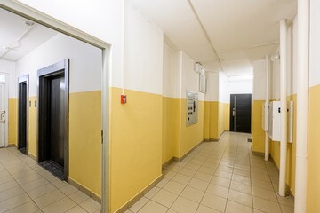 well-lit hallway with yellow and white walls, tiled floor, elevators, and doors