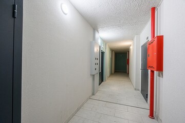 interior shot of a brightly lit hallway, with doors, lighting, and safety features