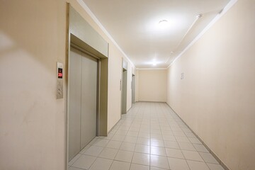 hallway with elevator doors, beige walls, and tiled floor. The number 20 is visible on the right wall