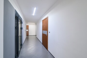 bright hallway with gray tiled floor, white walls, and a few doors, some with numbers