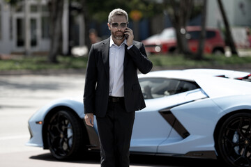 Business man in suit outdoors. Rich businessman next to a luxury car. Global business. Successful...