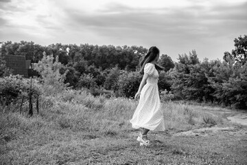 Portrait of a young beautiful dark-haired girl in a dress in the forest. Vintage black and white...