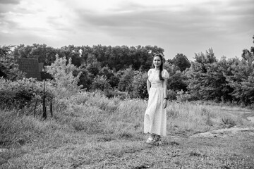 Portrait of a young beautiful dark-haired girl in a dress in the forest. Vintage black and white...