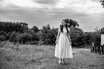 Portrait of a young beautiful dark-haired girl in a dress in the forest. Vintage black and white...
