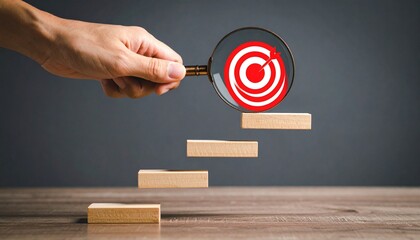 Magnifying glass over red target atop wooden staircase blocks.