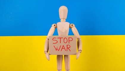 Wooden mannequin holding “STOP WAR” sign in front of blue-yellow backdrop, symbol of anti-war protest and peace advocacy
