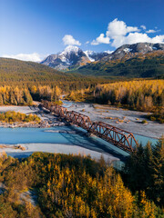 Aerial scenic view of rail road bridge over glacial river in Alaska during autumn time.