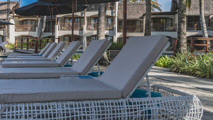 A row of sun loungers with soft mattresses on the outdoor terrace by the swimming pool. Pedestrian...