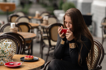 Coffee Dessert Woman: Brunette drinks coffee outdoors, eating dessert, relaxing on a summer afternoon in cafe.