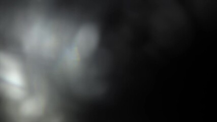 Minimal and moody abstract background with a soft, hazy cluster of white and grey bokeh lights that fade into a dark backdrop