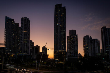 Panoramic view of the skyline of a modern city with tall buildings at sunset.