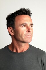 Obraz premium Pure white solid background. Classy men's mid fade haircut - midlife white man with black hair. Visual idea creative pattern of style for aging men. A sophisticated male posing with grace.