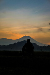 Silhouetted watcher surveys serene mountain vista