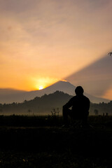 Sunrise silhouette Observing the misty volcano