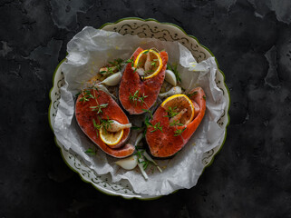 Slices of raw red fish with lemon, thyme, olive oil, spices in a baking dish. Cooking lunch