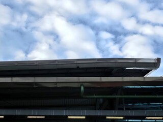 Obraz premium Modern building roof with pipes against a cloudy sky.