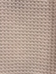 Close-up of a light beige waffle knit fabric texture.