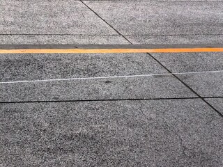 Orange painted curb and white string on textured concrete pavement.