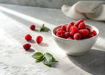 Fresh raspberries in a bowl with scattered berries and leaves