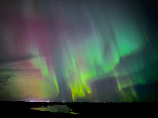 Northern Lights Aurora Borealis over the Missouri river at night town in the background 