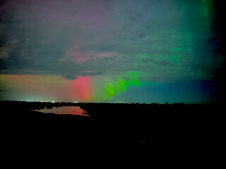 Northern lights over the missouri river with a rural town in the background. aurora borealis green red with clouds 